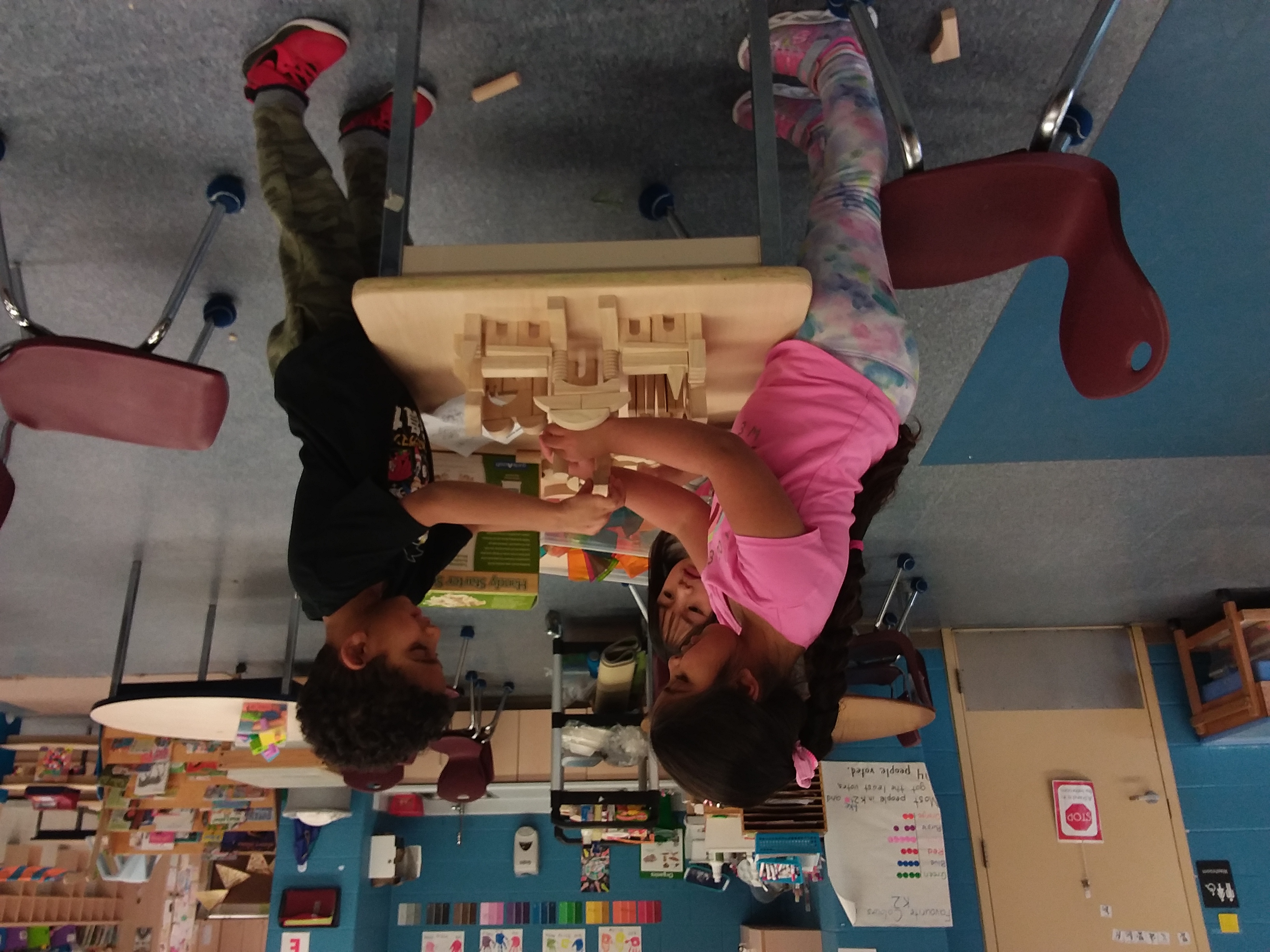 Three kindergarten child build a structure using wooden blocks in a PLASP program