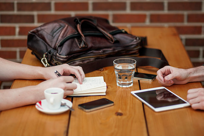 Two people writing over coffee