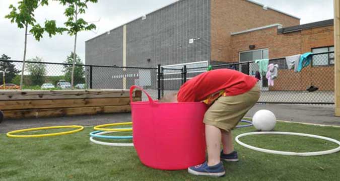 A child explores the inside of a large bucket 