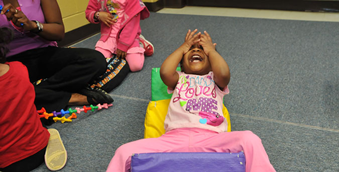 A child puts her hands to her face in a surprised reaction in a PLASP program