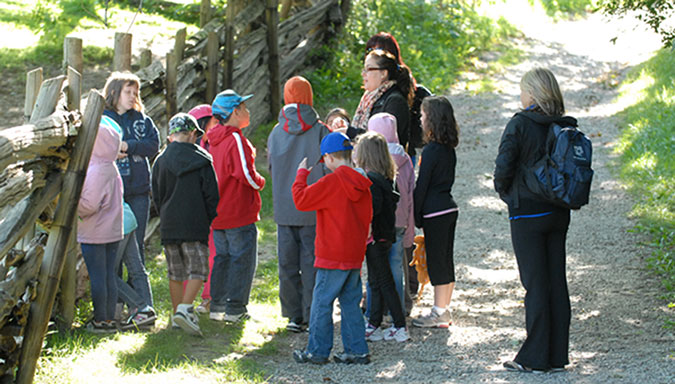 A group of PLASP staff and children take a pause while walking along a trail during an outdoor PLASP camp excursion. 