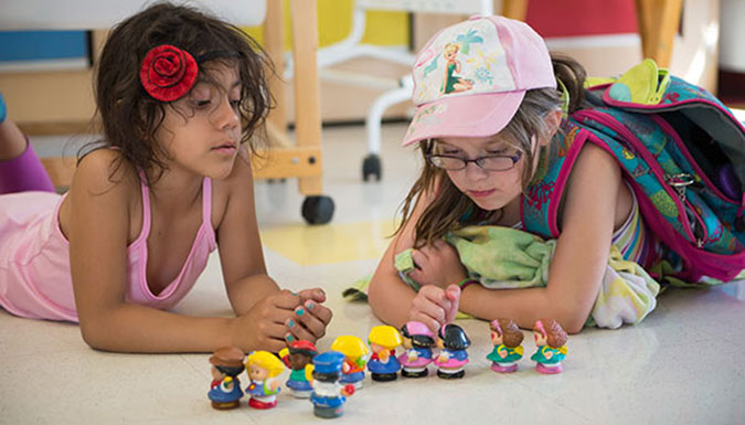 Two PLASP children play with miniature plastic figurines