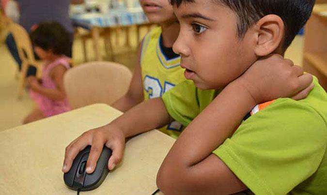 A child handles a computer mouse at a PLASP program. 