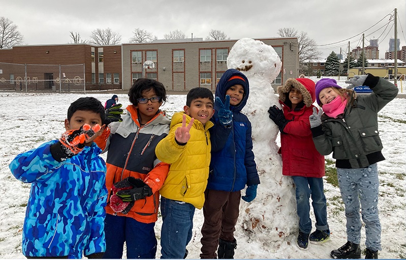 A group of PLASP children pose outside with a snowman