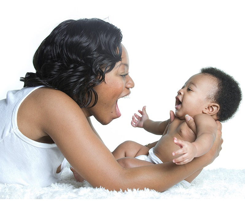 A mom holding her baby and smiling 